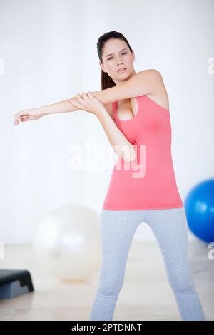 Ich mache mich bereit fürs Fitnessstudio. Eine junge Frau, die sich im Fitnessstudio dehnt Stockfoto