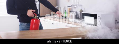 Feuerlöscher In Der Küche. Rauchgefahr Durch Mikrowellen Stockfoto