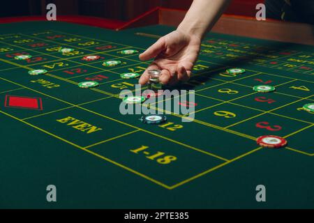 Kasino-Roulette-Tisch mit Chips und Karten. Eine Siegerkombination. Hand des Croupiers hinter dem Spieltisch. Stockfoto