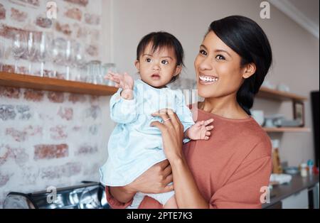 Invalidität, Mutter und Baby mit Down-Syndrom in einem glücklichen und schönen Familienhaus mit Kinderbetreuung am Wochenende. Mom und behindertes Mädchen mit speziellem Nager Stockfoto