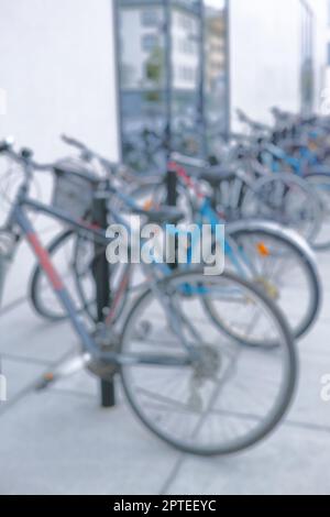 Bereit für die Fahrt. Verschwommenes Bild eines Fahrrads an einem Fahrradständer in einer Stadt Stockfoto