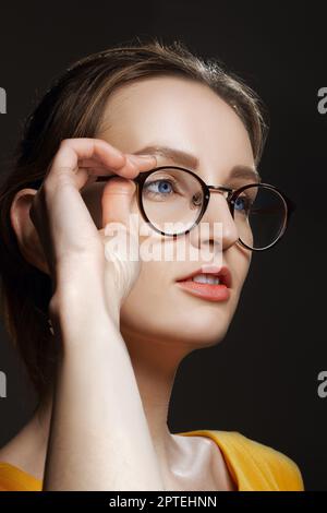 Porträt eines verdächtigen Mädchens, das sich mit einer Brille berührt Stockfoto