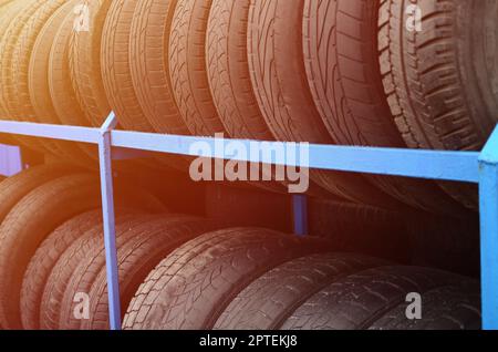 Rack mit verschiedenen Autoreifen im Automobilgeschäft. Viele schwarze Reifen. Hintergrund des Reifenstapels. Selektiver Fokus Stockfoto