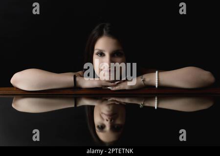 Low-Key-Porträt der Brünette junge Frau auf dem Spiegel liegen. Horizontal. Stockfoto