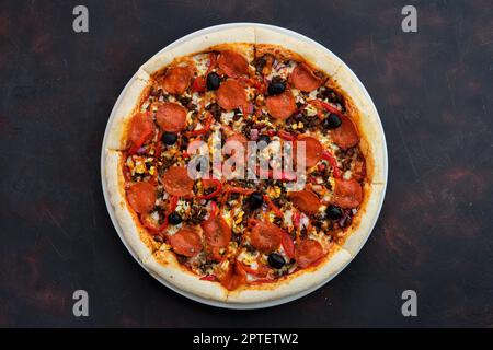 Blick von oben auf Pizza mit Forcemeat, Wurst, Paprika, Zwiebeln und Oliven Stockfoto