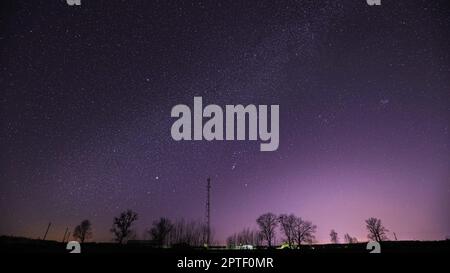 Real Night Sky Stars Über Der Landschaft Mit Telecommunications Cell Phone Tower Oder Mit Antenne. Natürlicher Sternenhimmel mit Milchstraßengalaxie über dem ländlichen C Stockfoto