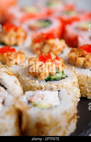 Traditionelle japanische Sushi-Rolle mit Thunfisch, rotem Tobiko-Kaviar und Gurke. Nahaufnahme eines Stücks Sushi, bedeckt mit weißen Sesamsamen und garniert mit Stockfoto