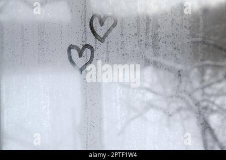 Zwei Herzen, die im Winter auf einem beschlagenen Glas gemalt wurden Stockfoto