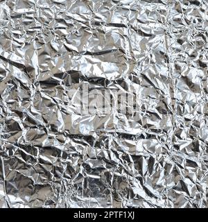 Dünnes, zerknittertes Blech aus zerkleinerter Aluminiumfolie mit glänzender, zerknitterter Oberfläche für Textur Stockfoto