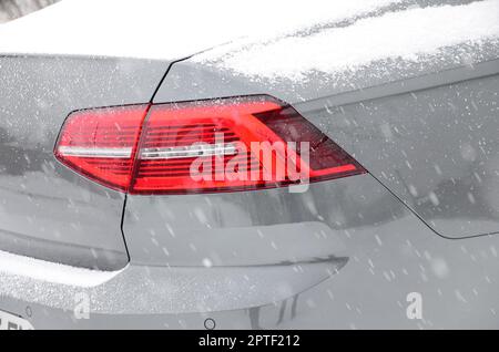 Fragment des Autos unter der Schneeschicht nach dem starken Schneefall. Die Karosserie des Autos ist mit weißem Schnee bedeckt Stockfoto