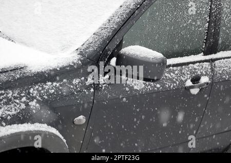 Fragment des Autos unter der Schneeschicht nach dem starken Schneefall. Die Karosserie des Autos ist mit weißem Schnee bedeckt Stockfoto