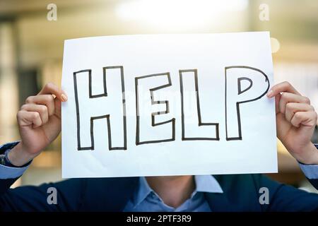 Jeder braucht ein bisschen Hilfe. Ein Geschäftsmann, der ein Schild hochhält und um Hilfe bittet Stockfoto