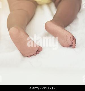 Diese Füße werden eines Tages große Fußabdrücke hinterlassen. Ein kleines Mädchen schläft zu Hause in einem Bett Stockfoto