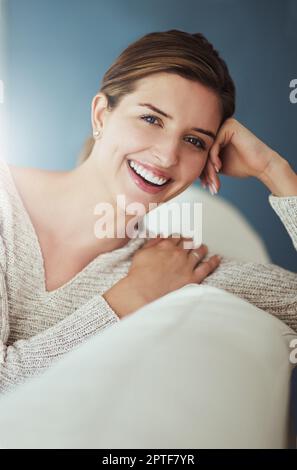 Manchmal muss man sich nur ein bisschen entspannen. Eine junge Frau, die sich zu Hause auf ihrem Sofa entspannt Stockfoto