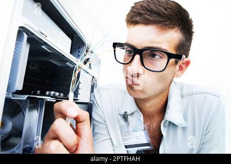 Sich auf die Lösung des Problems konzentrieren. Ein Techniker, der mit Kabeln an der Reparatur eines elektrischen Geräts arbeitet Stockfoto