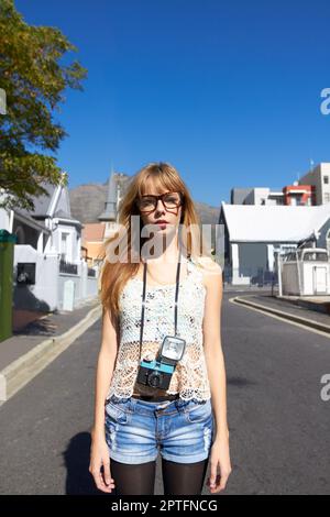 Auf der Suche nach der perfekten Aufnahme in die Stadt. Ein trendiges junges Mädchen mit einer alten Kamera in einer Wohngegend Stockfoto