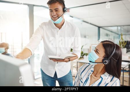 Covid, Mentor für Kundensupport und Web-Hilfe, unterstützt einen Berater für Online-Telefonie im Büro. Zufriedener Mitarbeiter des Internet-Callcenters und Teamleiter bei der Arbeit an Digit Stockfoto