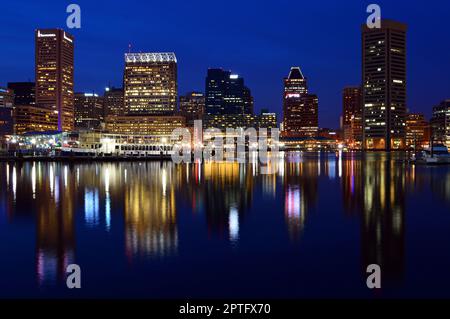 Die Lichter der Skyline von Baltimore sind beleuchtet und spiegeln sich im Wasser von Inner Harbor Stockfoto