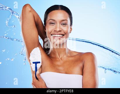 Schwarze Frau, Achselrasur mit Sahne und Rasierer, Schönheit für die Pflege, Wasserspritzer unter der Dusche mit blauem Studiohintergrund. Hygiene, Schaumstoff und Reinigung Stockfoto