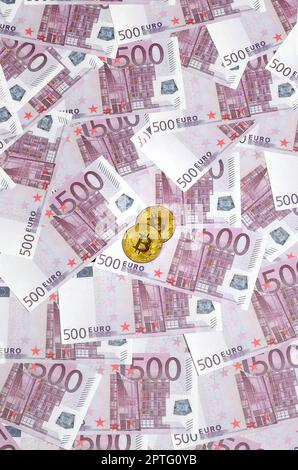 Bitcoins auf einem Stapel 500-Euro-Banknoten. Traditionelles Geld versus Kryptowährungskonzept. Goldmünze über 500-Euro-Scheine. Schließen Stockfoto