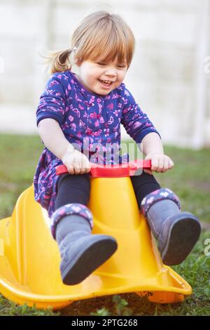 Sie liebt ihren Schaukelstuhl. Ein süßes Mädchen, das draußen auf einem Schaukelstuhl sitzt Stockfoto