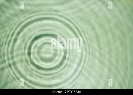 Entkokelt geriffelte, transparente, frisch-grüne Wasser-Gel-Oberfläche im Schwimmbad mit Flecken, Wellen und Schatten. Konzentrisch expandierende Kreise auf der Oberfläche von f Stockfoto