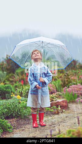 Mein Garten liebt den Regen. Die volle Länge eines jungen Mannes, der draußen im Regen steht Stockfoto