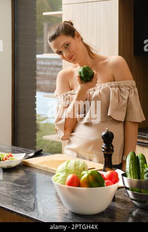 Eine Schwangerin hält frischen grünen Paprika in der Hand Stockfoto