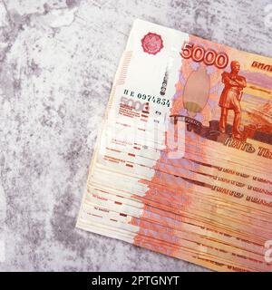 Russische Bargeld-Banknoten im Wert von 5.000 Rubel, das Bündel liegt auf grauem Hintergrund, es gibt Platz für eine Inschrift und Text. Layout, Modell. Stockfoto