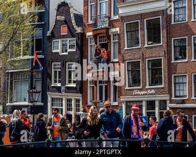 Amsterdam, Niederlande. 27. April 2023. Man sieht Leute, die die Boote auf den Kanälen beobachten. Der Königstag ist bekannt für eines der größten und farbenprächtigsten Feste des Landes, insbesondere in Amsterdam. Die Stadt ist voller Orange, während die Menschen die größte Straßenparty des Jahres genießen, die freien Märkte genießen und Spaß auf den Booten entlang der Kanäle haben. Kredit: SOPA Images Limited/Alamy Live News Stockfoto