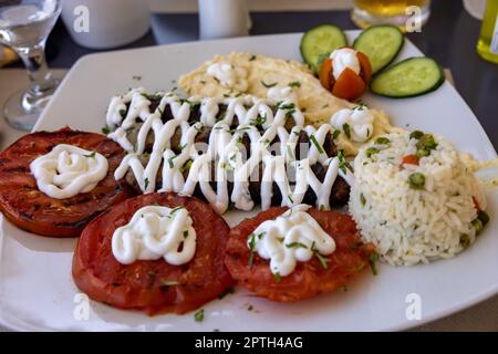 Gebratene Souvlaki und gegrillte Tomaten. Typisch leckeres griechisches Mittagessen Stockfoto