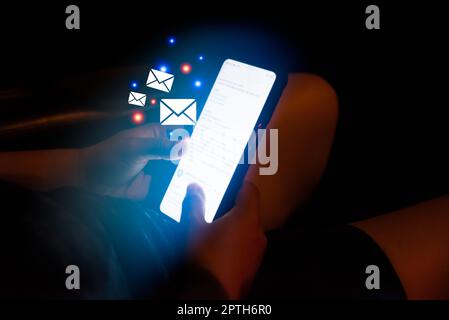 Frau Hand hält ein Telefon Überprüfung E-Mail-Symbol virtuellen Bildschirm im Auto in der Nacht.Digitale Technologie Verbindung Anwendung Nachricht Business-Konzept. Stockfoto