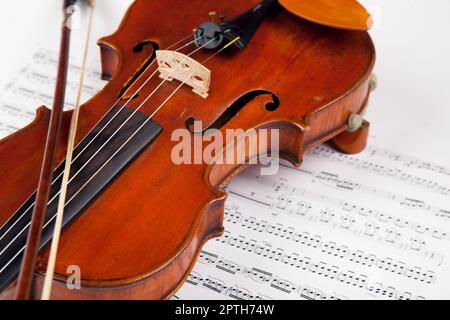 Blatt, Musik und Klassik mit Geige auf Papier für Orchester, Vintage und antike Instrumente. Notizen, Retro-Kunst und Kultur mit Nahaufnahme aus Holz Stockfoto