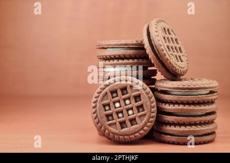 Haufen Chocolate Chip Cookies mit Weiße Vanille Creme gefüllt liegt auf Holz- braune Oberfläche. Süßes und leckeres Sandwich runde Kekse. Detaillierte essen Ph Stockfoto