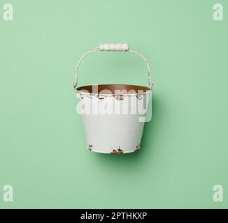 Miniatur kleiner weißer Eimer auf grünem Hintergrund, Draufsicht Stockfoto