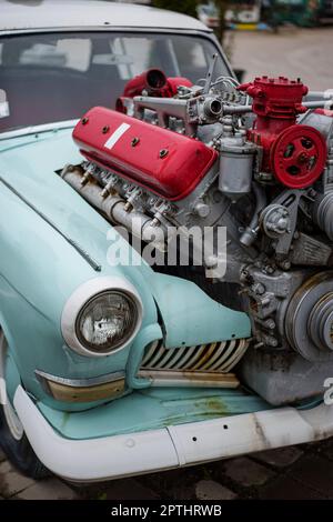 Bild eines getunten Oldtimers mit einem großen Motor, der aus der Motorhaube ragt. Stockfoto