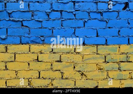 Eine alte Mauer in den Farben der Ukrainische Flagge bemalt. Gelb und Blau auf einem verlassenen und beschädigte Mauer. Das Konzept der Stärke von Stockfoto