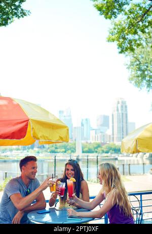 Auf den Sommer. Drei junge Freunde sitzen in einem Café im Freien. Stockfoto