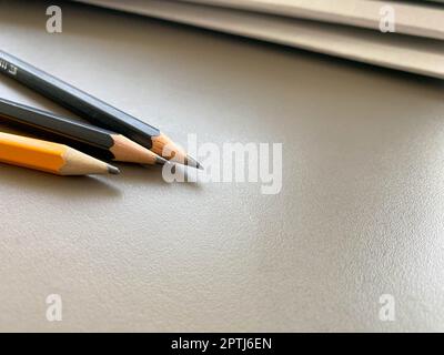 Drei Bleistifte liegen scharf gespitzt neben Ordnern mit Blättern und Dokumenten auf dem Büroschreibtisch im Büro. Briefpapier. Stockfoto