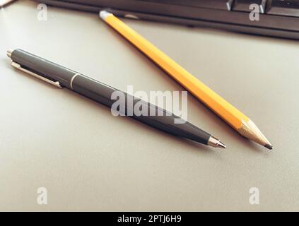 Schreibwaren auf dem Tisch im Büro. Ein blauer Metallstift zum Schreiben, ein einfacher Holzbleistift mit Mine. Schreibwerkzeug. Stockfoto