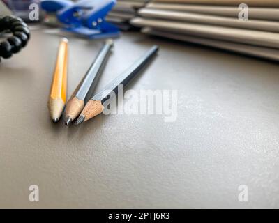 Drei Bleistifte liegen scharf gespitzt neben Ordnern mit Blättern und Dokumenten auf dem Büroschreibtisch im Büro. Briefpapier. Stockfoto