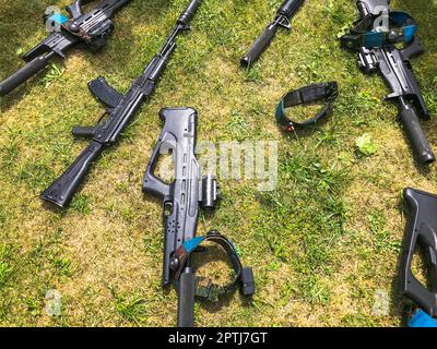 Schwarze Eisenmaschinengewehre der Armee, kleine Waffen für Soldaten mit Schalldämpfern liegen auf grünem Gras. Stockfoto