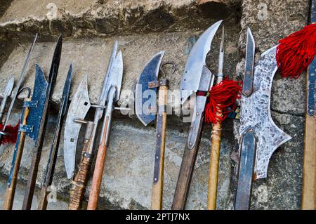 Die alten mittelalterlichen kalten Waffen, Äxte, Olibarden, Messer, Schwerter mit Holzgriffen lecken auf den Steintreppen des Schlosses. Stockfoto