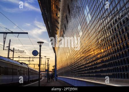 Bahnhof in den goldenen Zeiten mit Nachglühen auf der Glasfassade eines Gebäudes Stockfoto