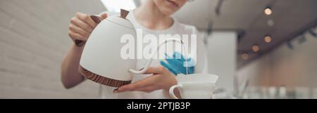 Barista gießt gekochtes Wasser durch den Filter in den Becher Stockfoto