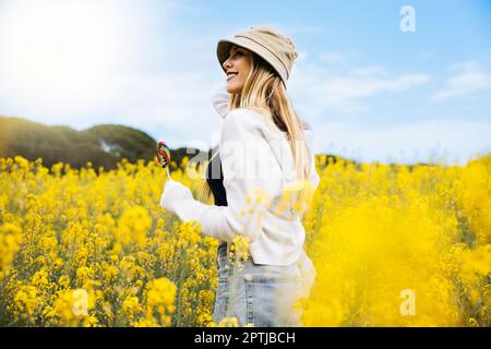 Ein hübsches blondes Mädchen posiert inmitten eines Feldes blühender gelber Rapsblumen Stockfoto