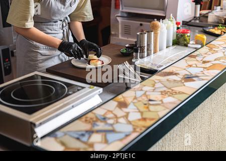Nahaufnahme des Küchenchefs dekorieren Sie Käsekuchen, bevor Sie zum Frühstück in der Restaurantküche servieren Stockfoto