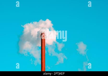 Konzept der weltweiten Umweltverschmutzung. Fabrik Schornstein weht Rauch aus Rohr in blauen Himmel Hintergrund während der Winterzeit Stockfoto