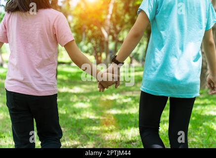 Zwei Schwester halten sich am warmen Frühlingstag im Park die Hände. Happy Friendship Familienkonzept. Stockfoto