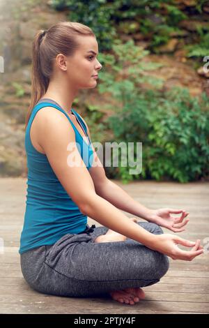 Frieden ist alles, was ich brauche. Eine junge Frau, die draußen Yoga praktiziert Stockfoto